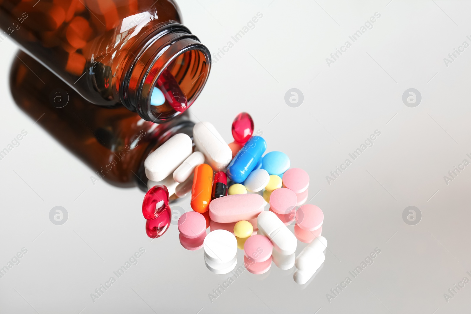 Photo of Bottle with pills on reflective surface