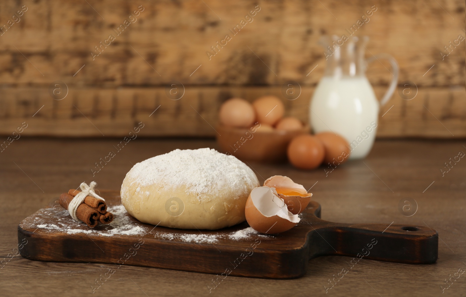 Photo of Raw eggs, dough and cinnamon on wooden table. Baking pie