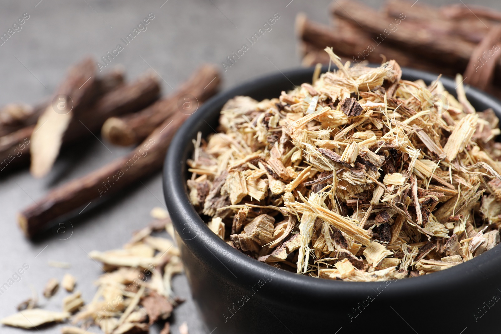 Photo of Dried sticks of liquorice root and shavings on grey table, closeup