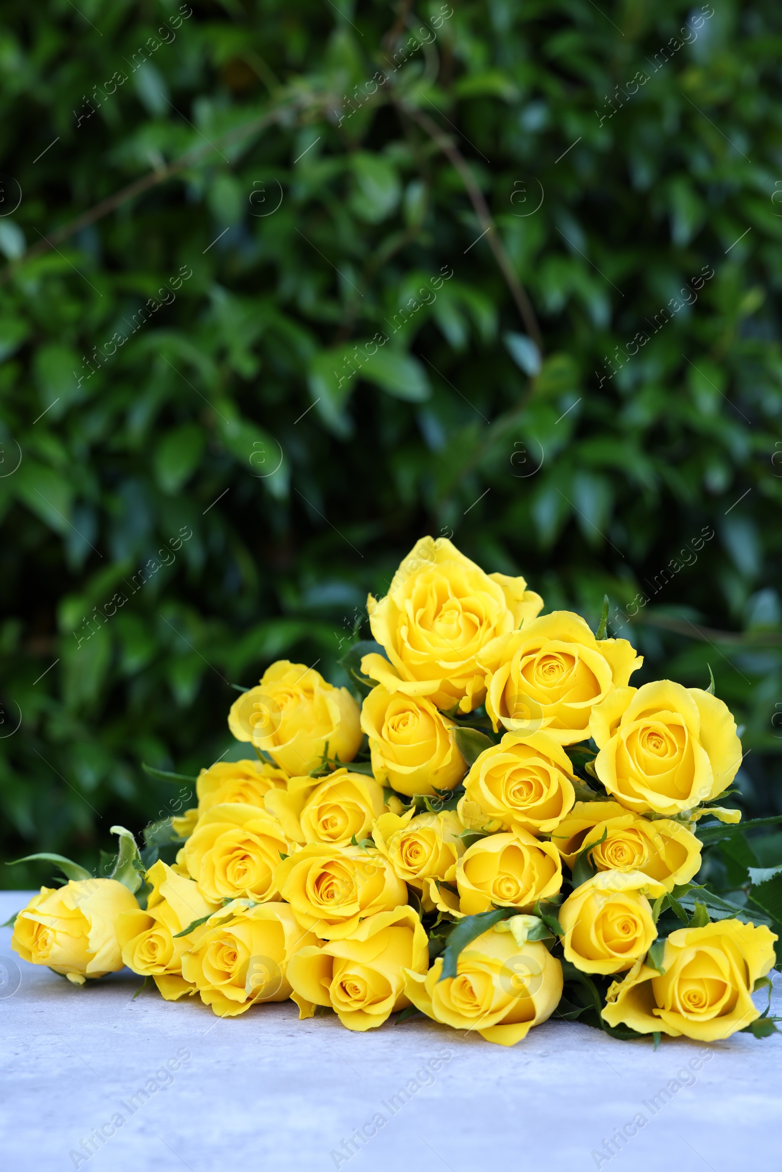 Photo of Beautiful bouquet of yellow roses on light table outdoors, space for text