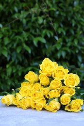 Beautiful bouquet of yellow roses on light table outdoors, space for text