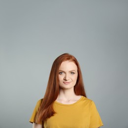 Photo of Candid portrait of happy young woman with charming smile and gorgeous red hair on grey background