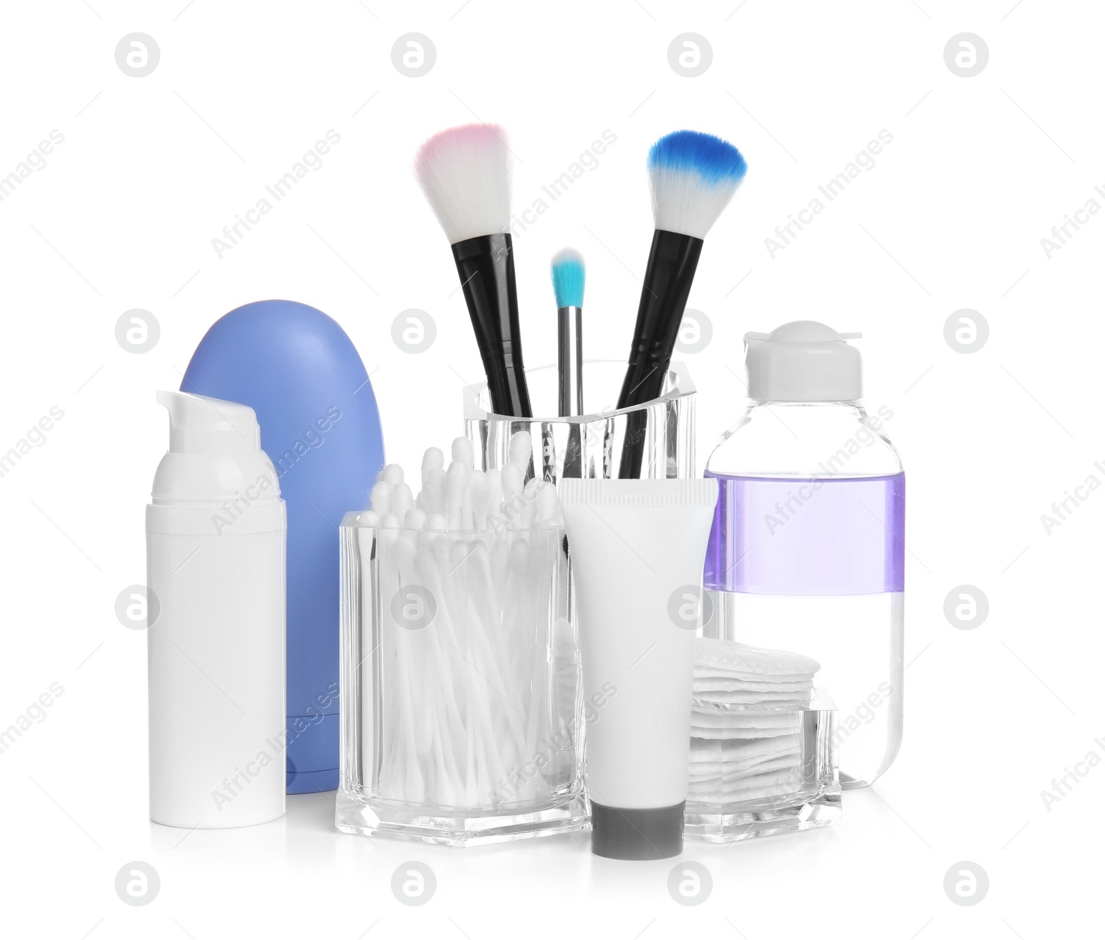 Photo of Cosmetic products near holder with brushes, cotton swabs and pads on white background