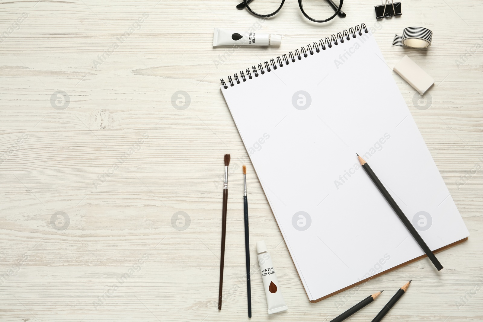 Photo of Flat lay composition with blank sketchbook on white wooden table. Space for text