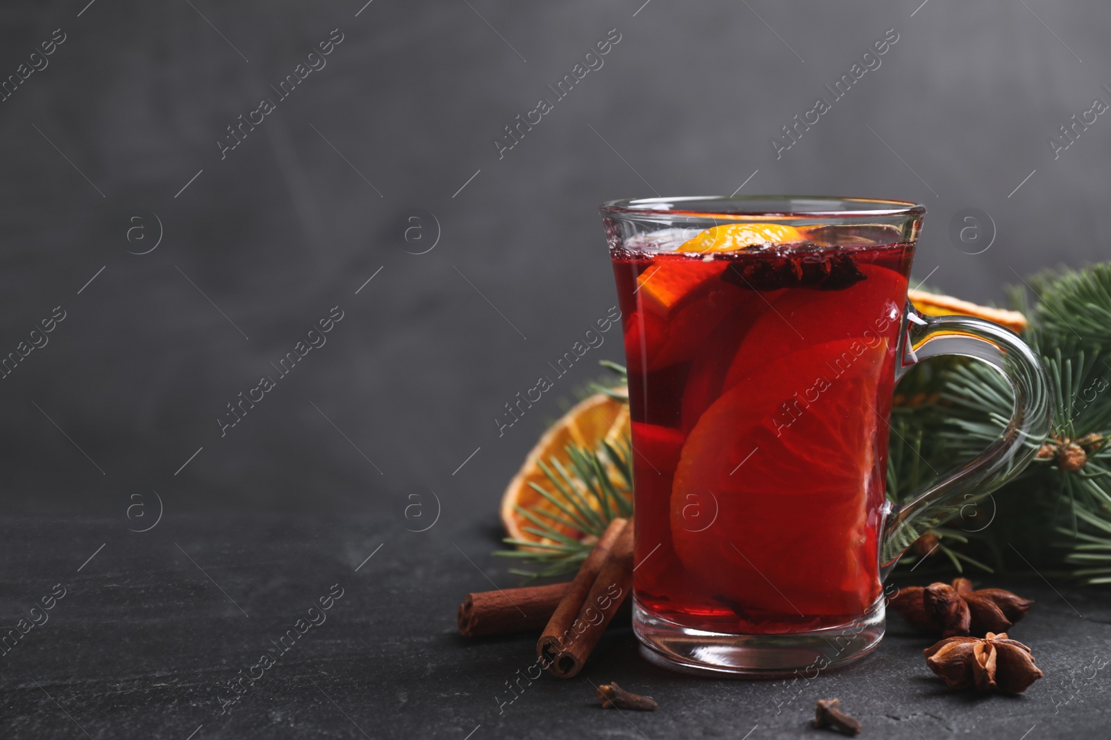 Photo of Tasty aromatic mulled wine on black table, space for text