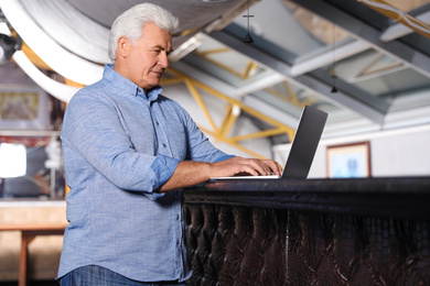 Photo of Senior business owner working with laptop in his restaurant