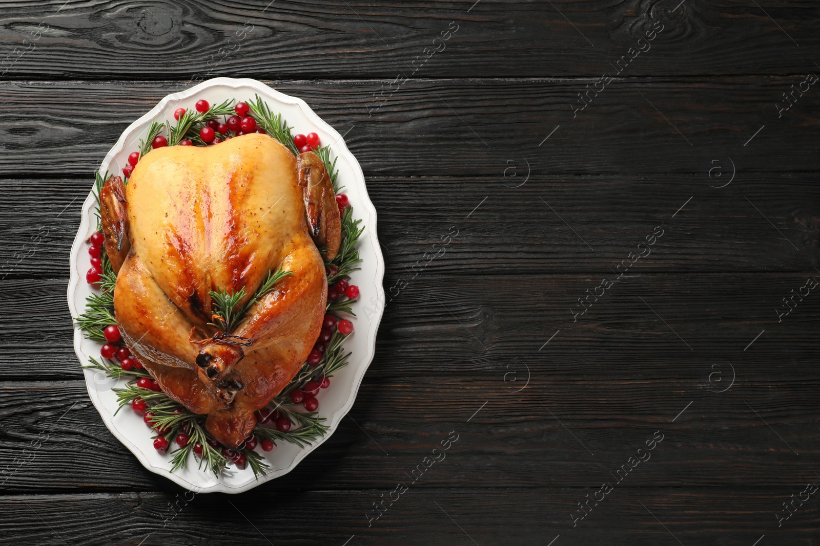 Photo of Platter of cooked turkey with garnish on wooden background, top view. Space for text