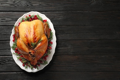 Photo of Platter of cooked turkey with garnish on wooden background, top view. Space for text