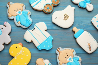 Cute tasty cookies of different shapes on light blue wooden table, flat lay. Baby shower party