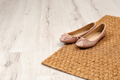 Photo of New clean doormat with shoes on floor. Space for text