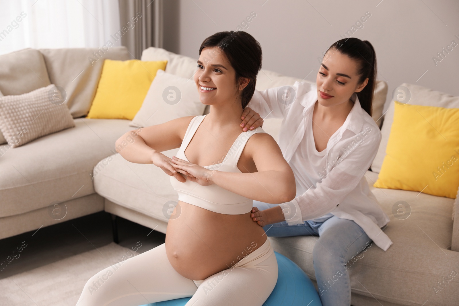 Photo of Doula working with pregnant woman in living room. Preparation for child birth