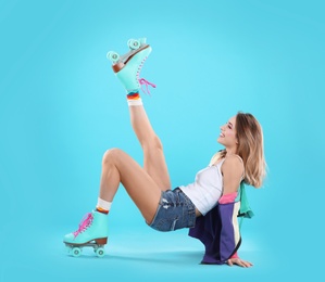 Young woman with retro roller skates on color background