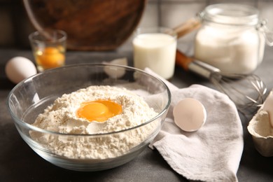 Making dough. Flour with egg yolk in bowl on grey table, closeup