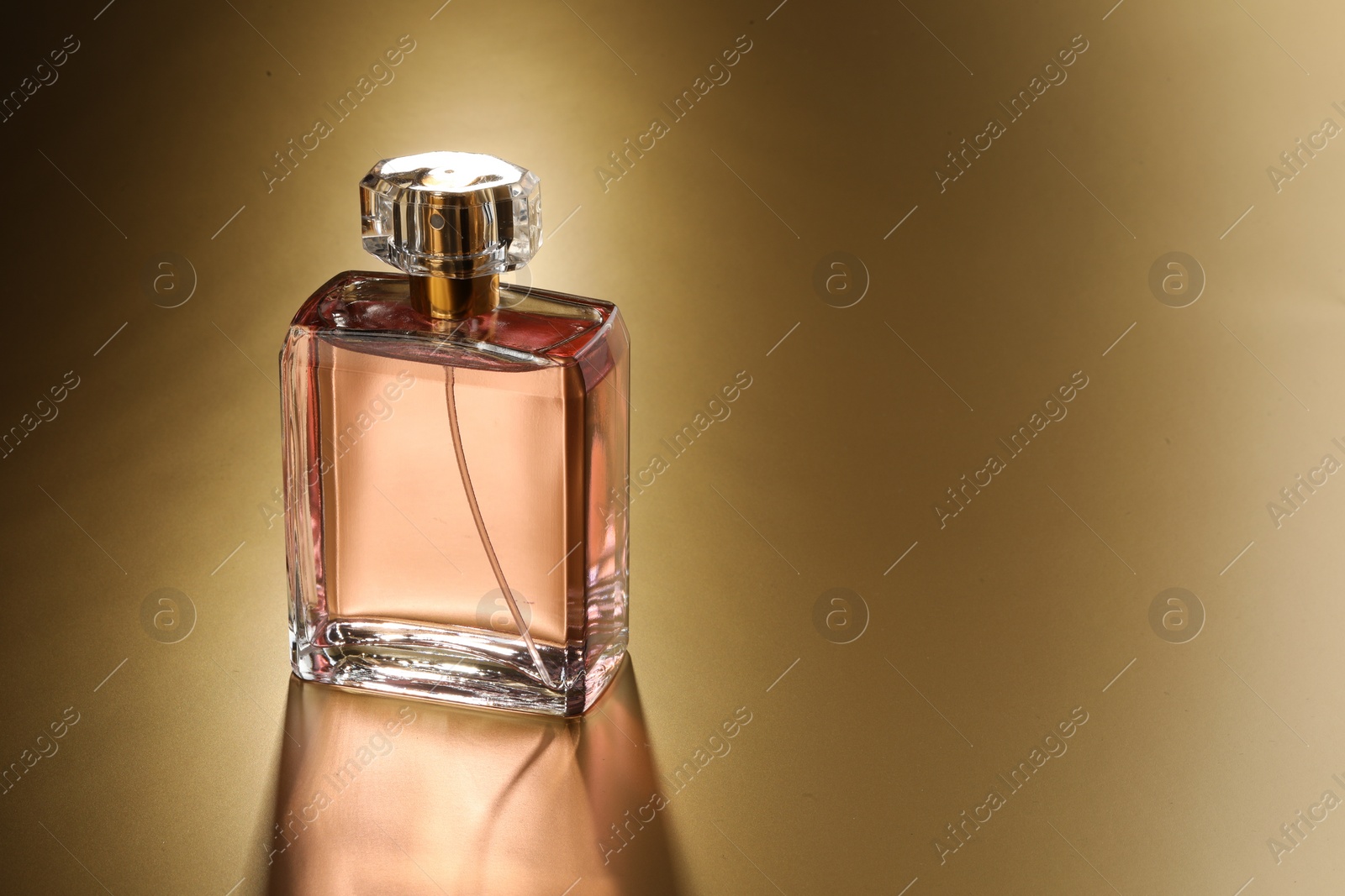 Photo of Luxury women's perfume. Sunlit glass bottle on golden background, space for text