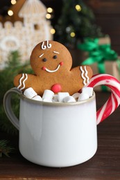 Gingerbread man in cup on wooden table, closeup