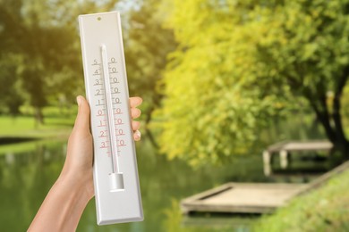 Image of Woman holding thermometer in park on sunny day, closeup