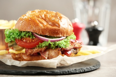 Photo of Delicious burger with bacon on slate plate