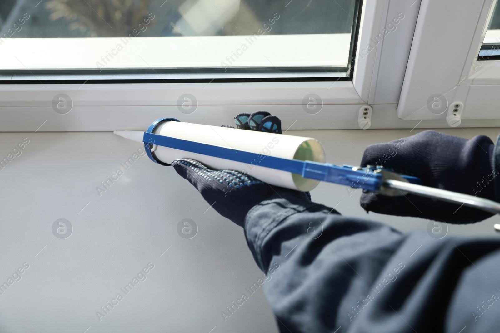 Photo of Construction worker sealing window with caulk, closeup