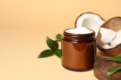 Photo of Jar of coconut face cream on light orange background. Space for text