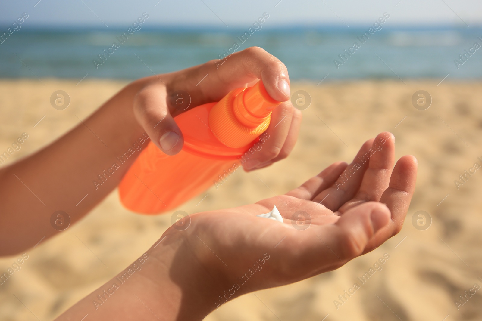 Photo of Child applying sunscreen near sea, closeup. Sun protection care