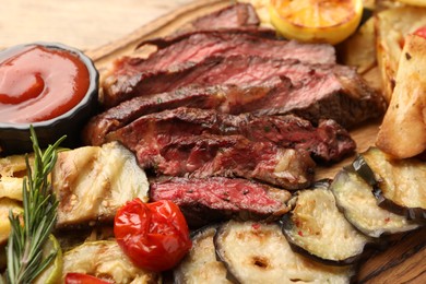 Photo of Delicious grilled beef with vegetables, tomato sauce and spices on table, closeup