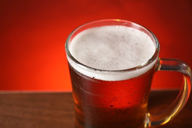 Photo of Mug with fresh beer on table against red background, closeup. Space for text