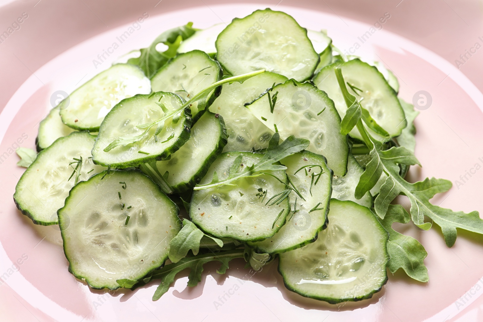 Photo of Delicious cucumber salad with arugula on plate, closeup