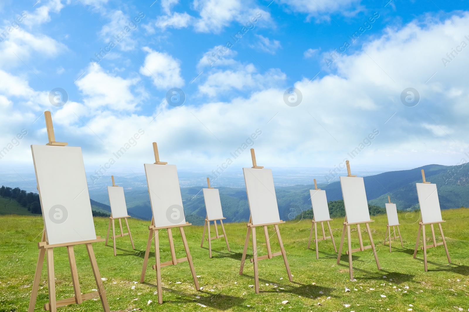 Image of Wooden easels with blank canvases in mountains on sunny day 