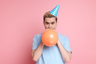 Photo of Young man with party hat and balloon on pink background