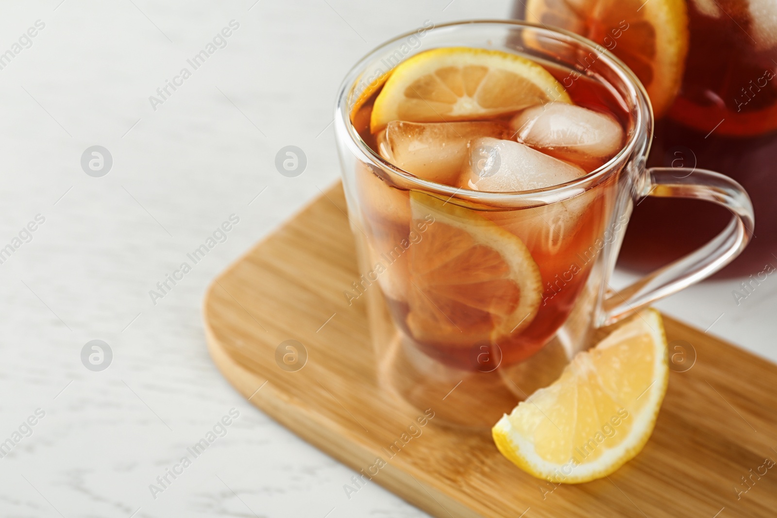 Photo of Cup and jug of refreshing iced tea on white table