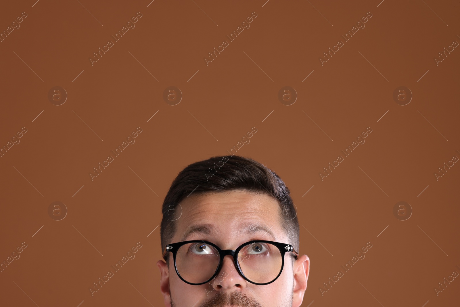 Photo of Man in stylish glasses on brown background, closeup