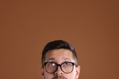 Photo of Man in stylish glasses on brown background, closeup