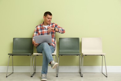 Man with laptop waiting for job interview indoors