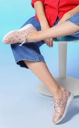 Photo of Woman in stylish shoes on stool against color background, closeup