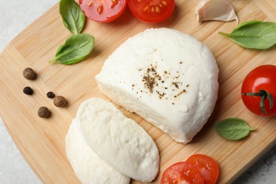 Delicious mozzarella with tomatoes and basil leaves on wooden board, above view
