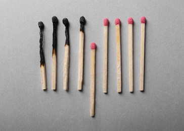 Photo of Burnt and whole matches on light grey background, flat lay. Stop destruction by breaking chain reaction concept