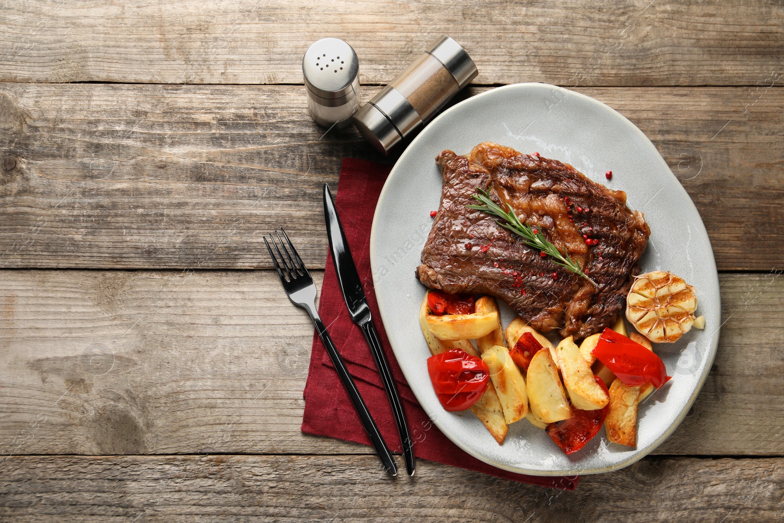 Photo of Delicious grilled beef steak and vegetables served on wooden table, top view. Space for text