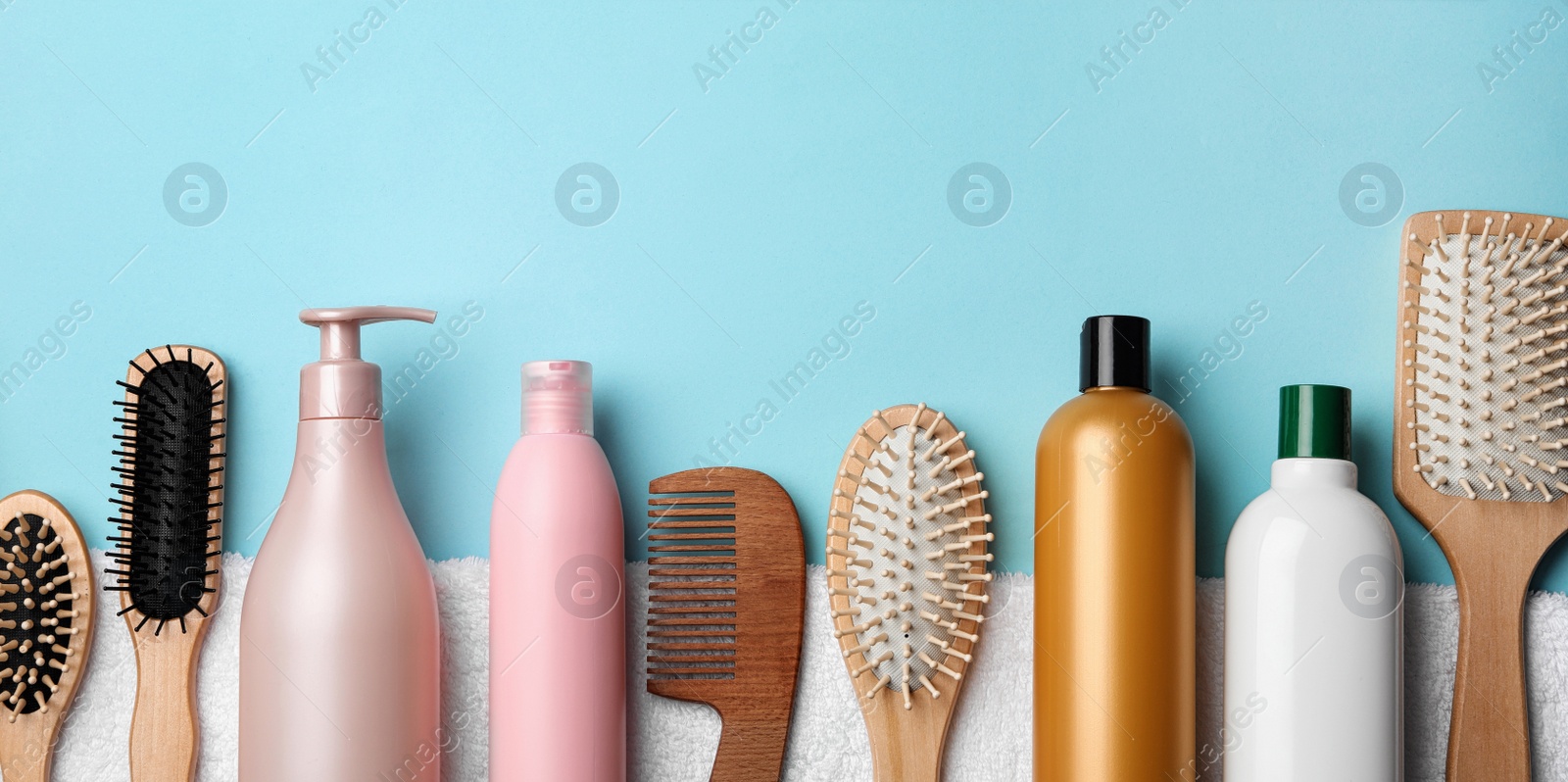 Image of Set with hair cosmetic products and tools on light blue background, flat lay. Banner design