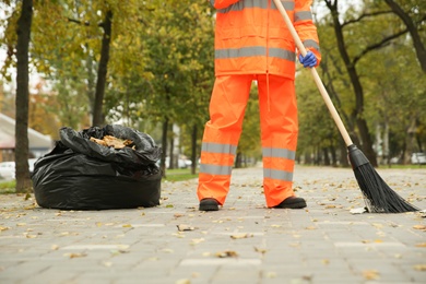 Photo of Street cleaner sweeping fallen leaves outdoors on autumn day, closeup