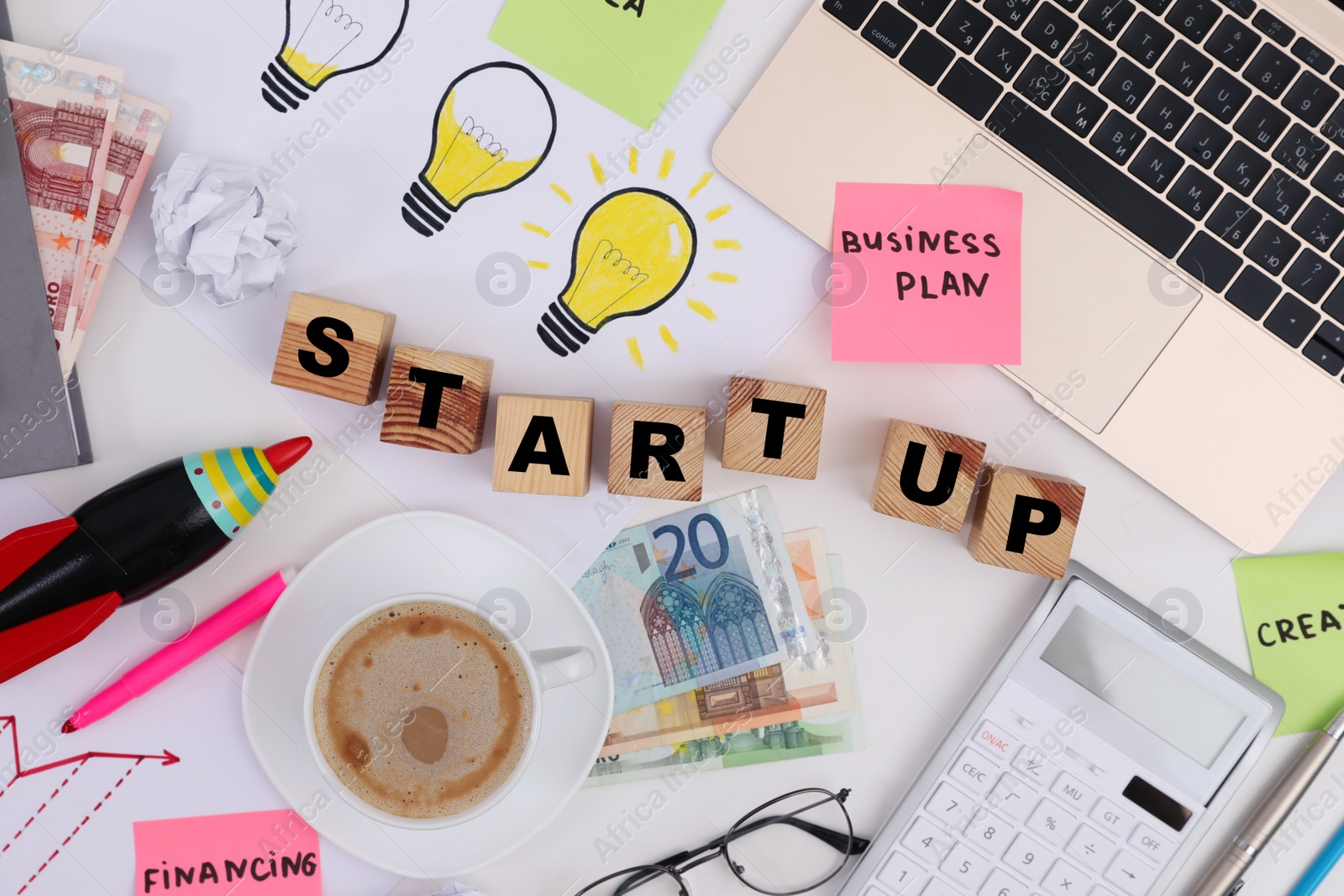 Photo of Flat lay composition of wooden cubes with words Start Up, money and stationery on white table