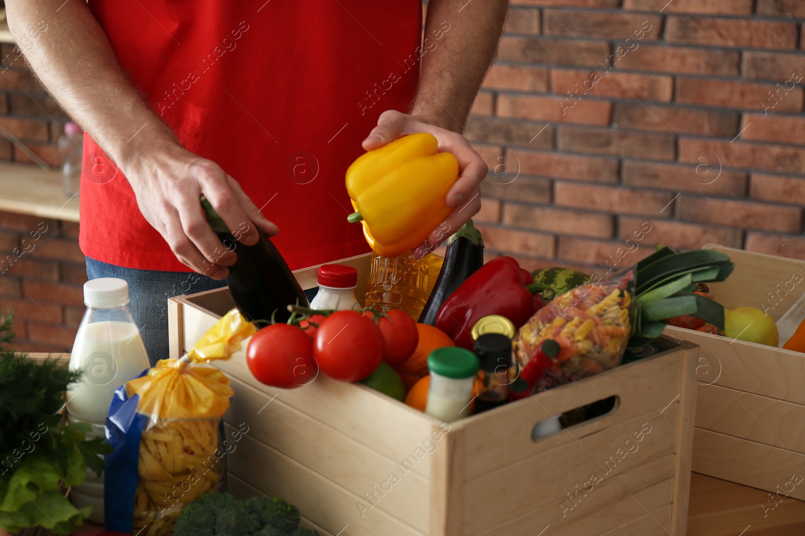 Photo of Man with fresh products at table indoors, closeup. Food delivery service