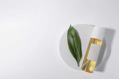 Photo of Bottle with cosmetic oil and green leaf on white background, top view. Space for text