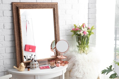 Table with beautiful mirror and cosmetics in modern makeup room