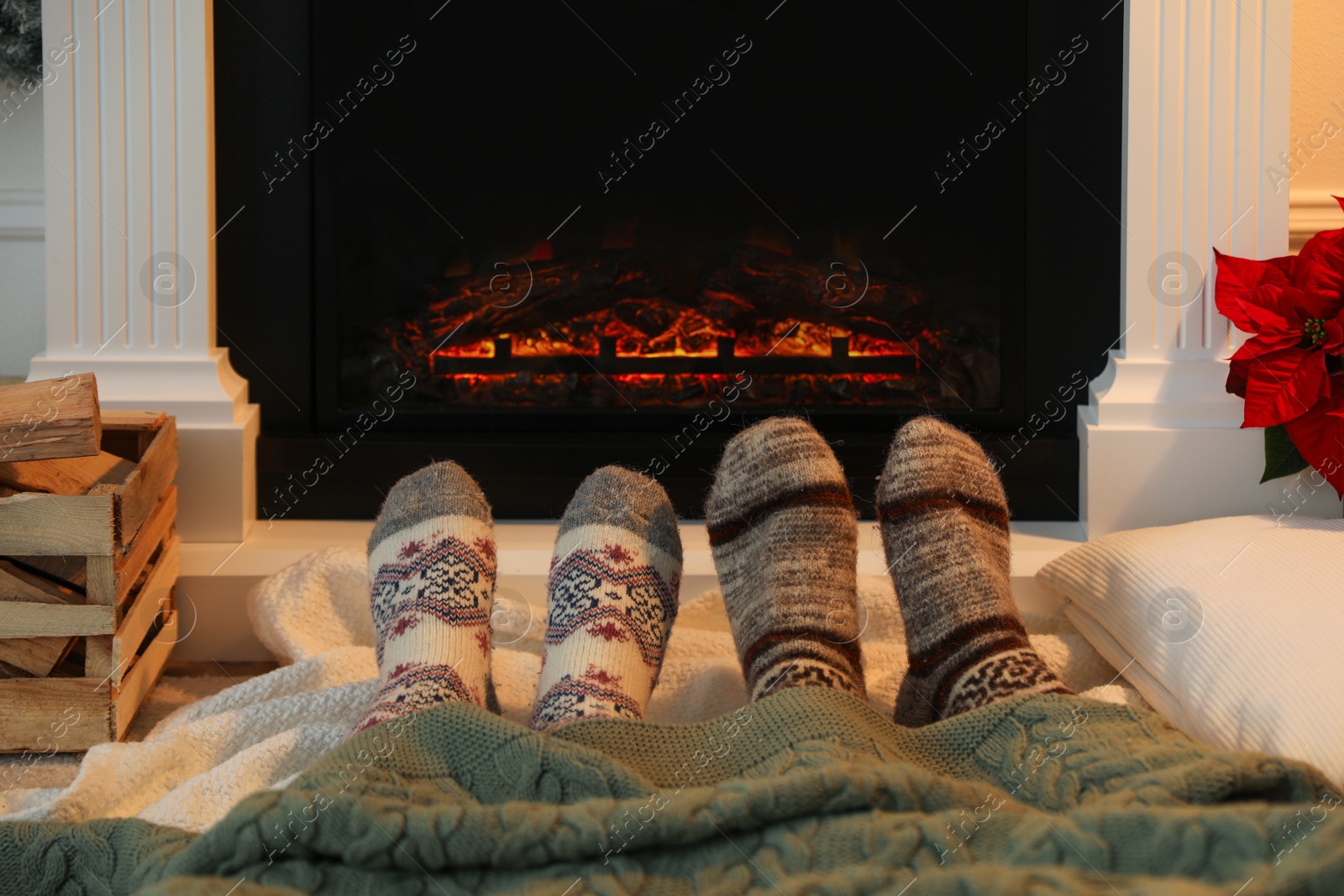 Photo of Couple in warm socks resting near fireplace at home, closeup