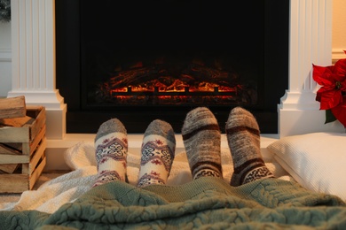 Couple in warm socks resting near fireplace at home, closeup