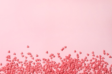 Heart shaped sprinkles on pink background, flat lay. Space for text