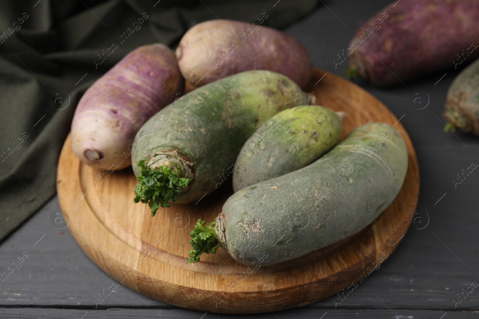 Photo of Green and purple daikon radishes on gray wooden table, closeup