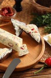 Photo of Tasty butter, dill, chili pepper and rye bread on wooden table