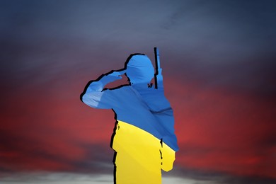 Image of Silhouette of soldier in color of Ukrainian flag with assault rifle against sky at sunset