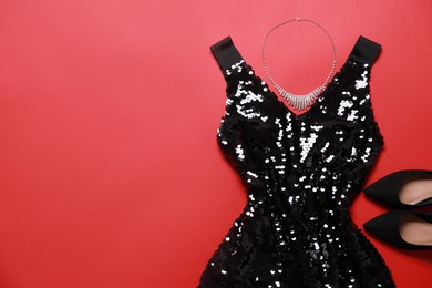 Photo of Beautiful dress, necklace and shoes on red background, flat lay with space for text. Rental clothing service